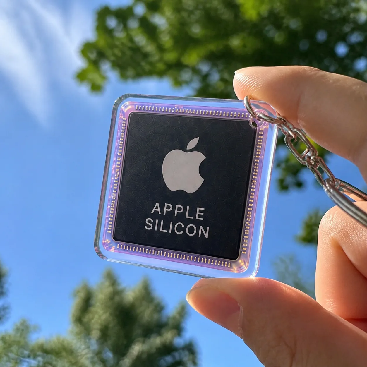 Apple Silicon acrylic collectible held against a blue sky